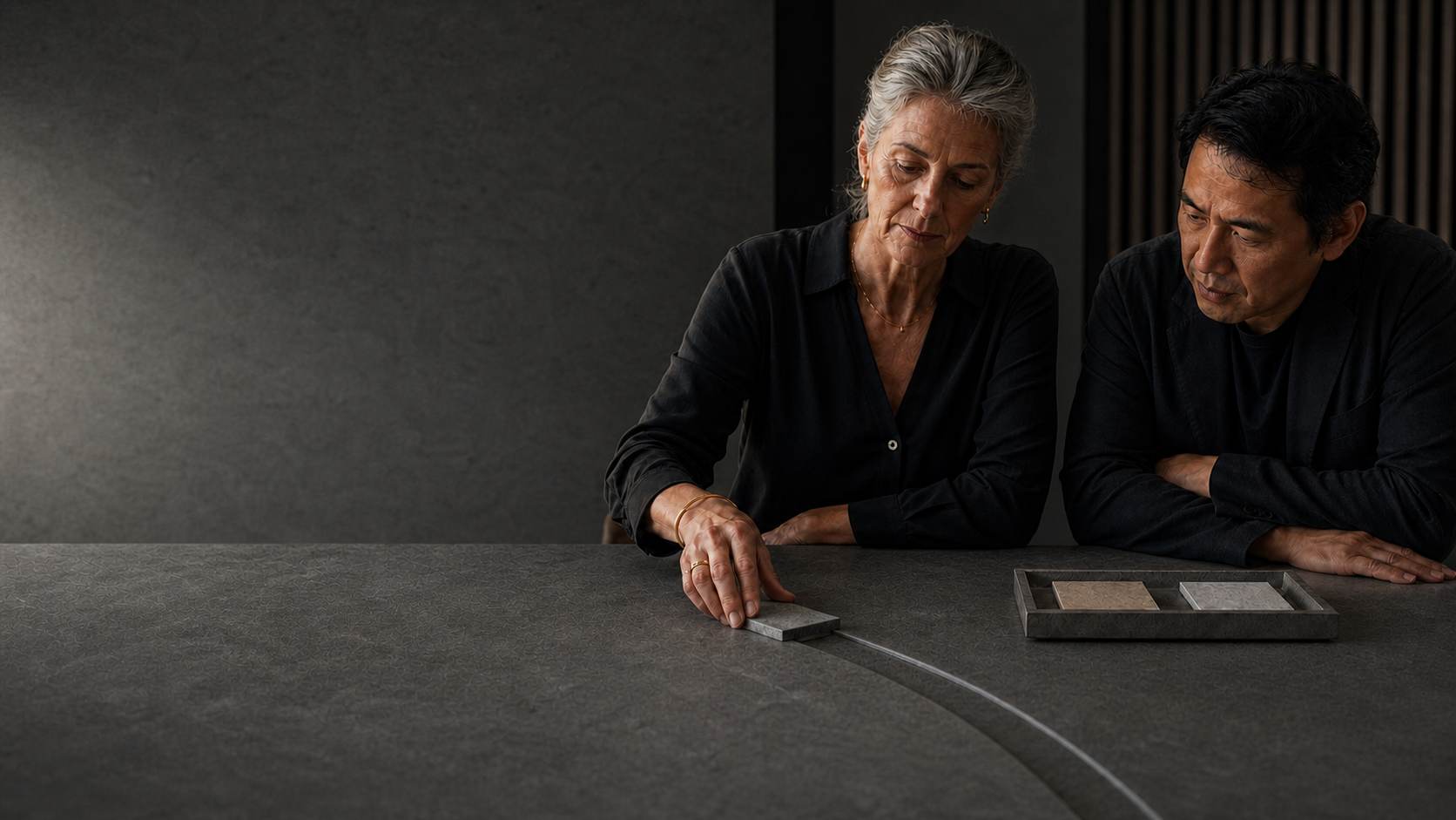 Two people examine material samples beside a precise illuminated route on a stone table.