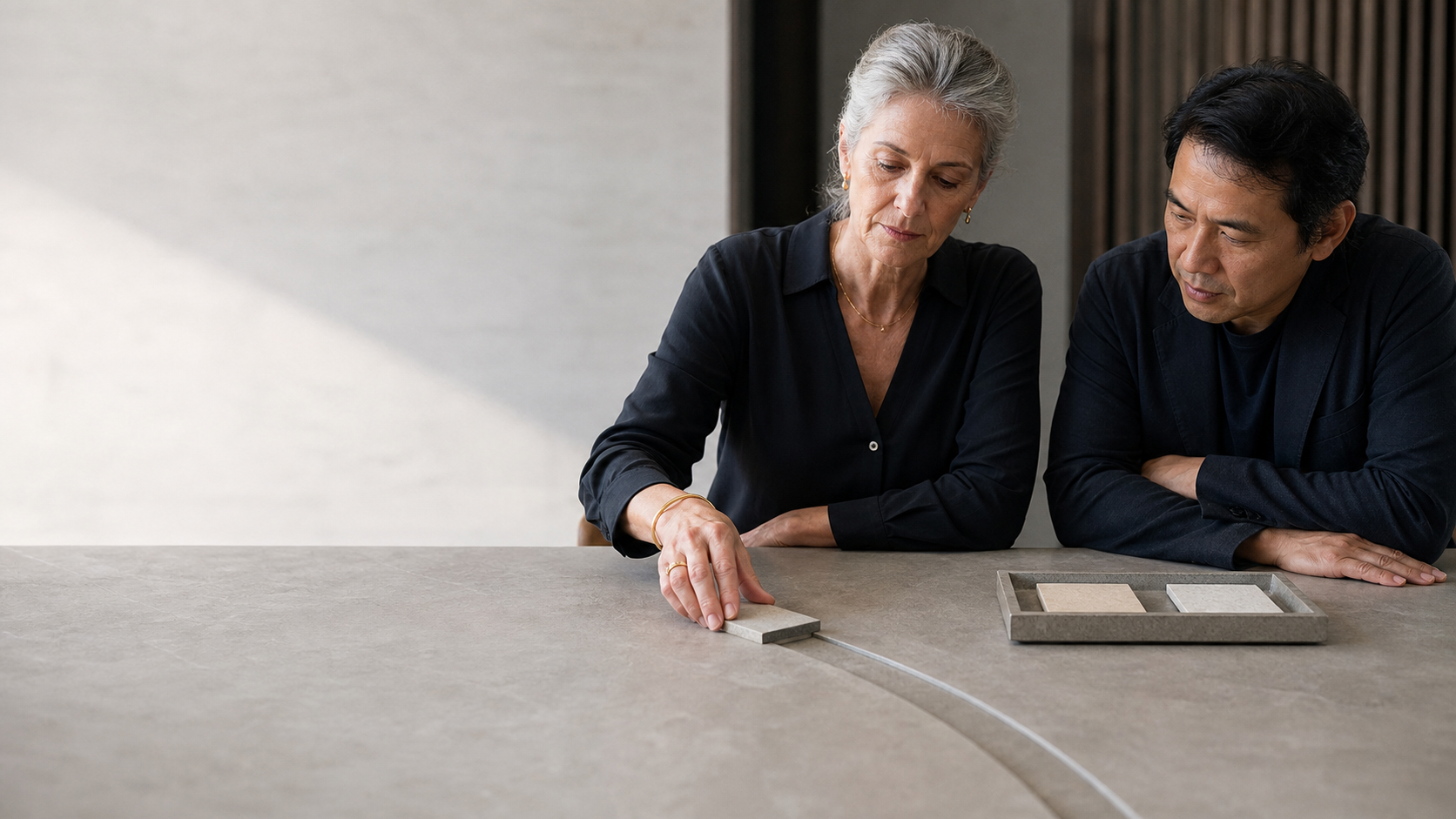 Two people examine material samples beside a precise illuminated route on a stone table.