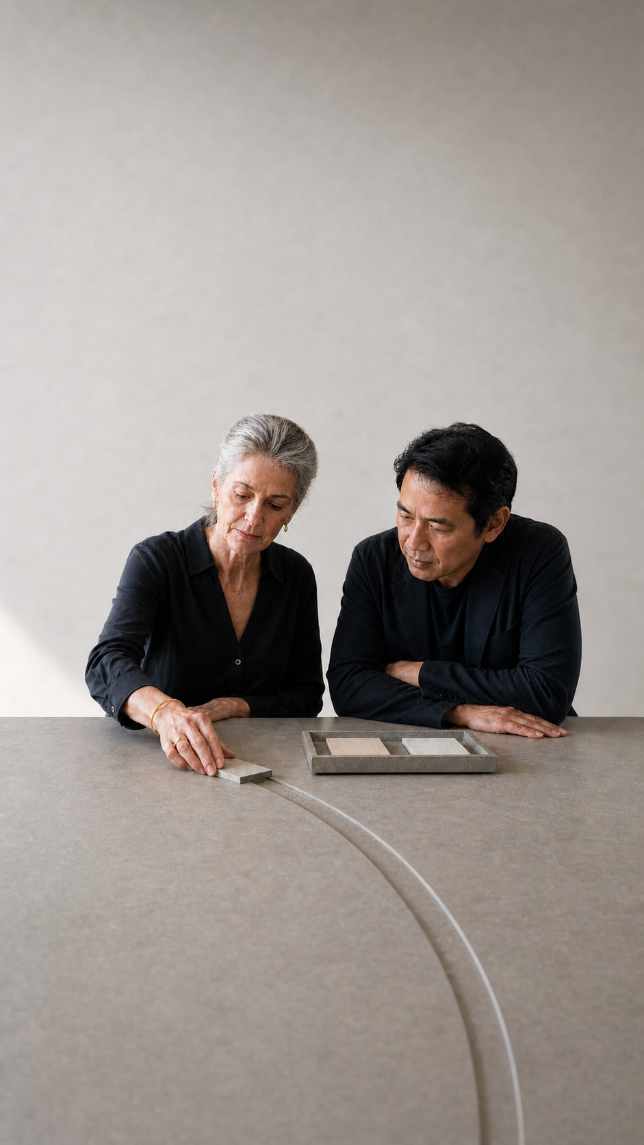 Two people examine material samples beside a precise illuminated route on a stone table.